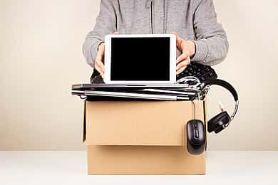 Woman hands holding digital tablet. Cardboard box full old used computers, phones, gadget devices for recycling. Planned obsolescence, e-waste, donation, electronic waste for reuse and recycle concept
